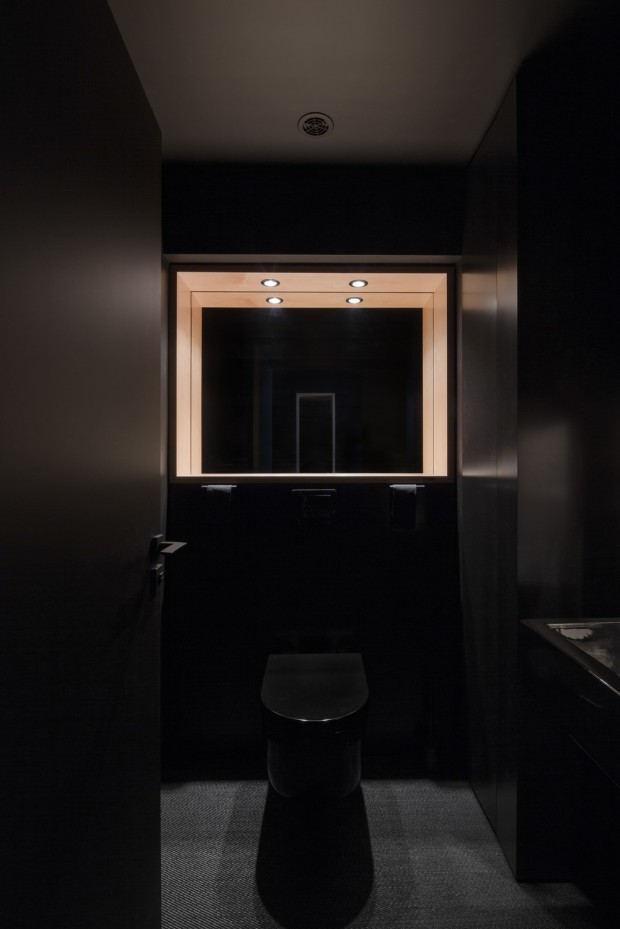 Cette image montre un WC suspendu design de taille moyenne avec un placard à porte plane, des portes de placard noires, un mur noir, un plan vasque, un plan de toilette en surface solide, un sol noir et un plan de toilette noir.