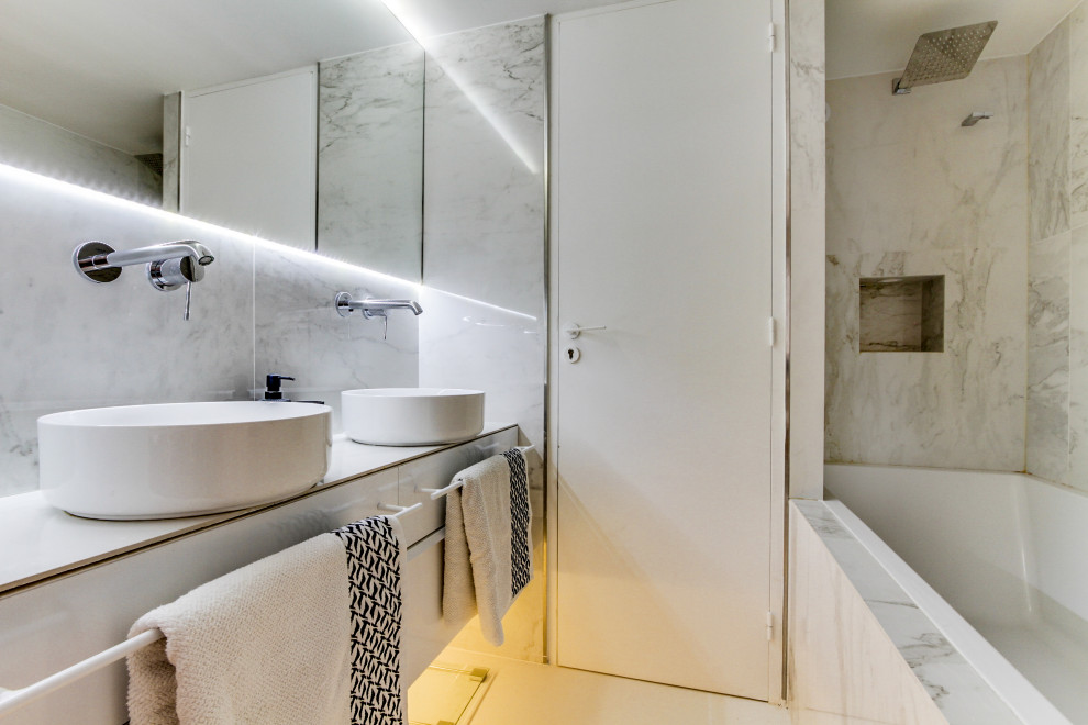 Cette image montre une salle de bain design avec un placard à porte plane, des portes de placard blanches, une baignoire posée, un combiné douche/baignoire, une vasque, un sol blanc, aucune cabine, un plan de toilette blanc, meuble double vasque et meuble-lavabo suspendu.