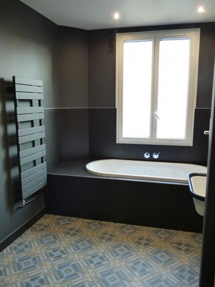 Design ideas for a medium sized contemporary ensuite bathroom in Paris with a submerged bath, a built-in shower, a wall mounted toilet, cement tiles, black walls, ceramic flooring, a wall-mounted sink, glass-front cabinets, black cabinets and grey tiles.