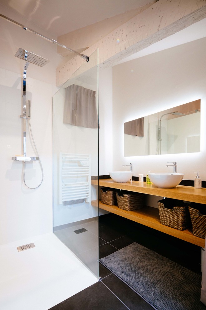 Идея дизайна: ванная комната среднего размера в скандинавском стиле с душем без бортиков, раздельным унитазом, белой плиткой, черной плиткой, цементной плиткой, белыми стенами, душевой кабиной, настольной раковиной, столешницей из дерева, открытым душем и коричневой столешницей