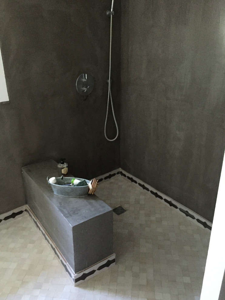 Medelhavsstil inredning av ett litet badrum med dusch, med en kantlös dusch, beige kakel, stenkakel och grå väggar
