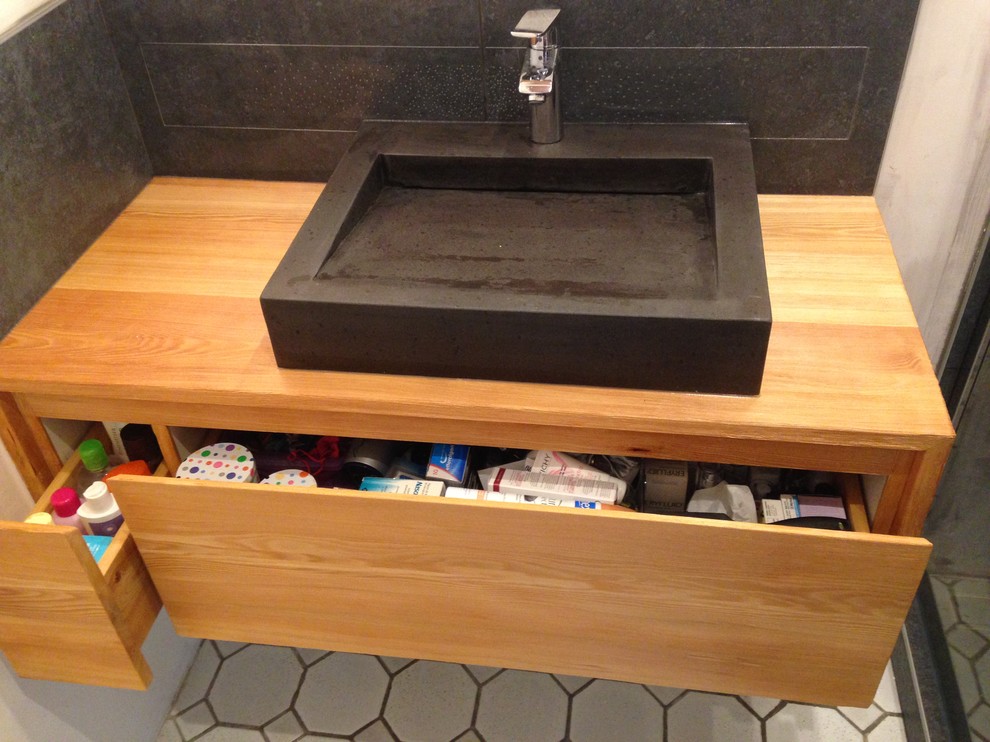 Imagen de cuarto de baño minimalista con lavabo encastrado, puertas de armario de madera clara, encimera de madera, baldosas y/o azulejos de cerámica y paredes negras