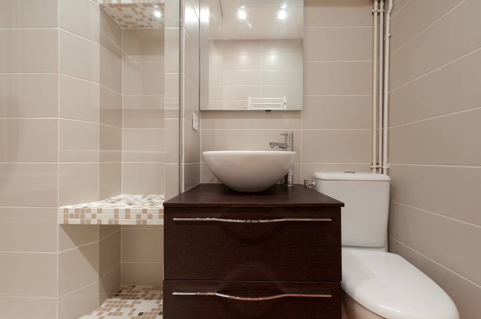 Bild på ett mellanstort funkis badrum med dusch, med ett fristående handfat, luckor med profilerade fronter, skåp i mörkt trä, träbänkskiva, en kantlös dusch, beige kakel, mosaik och beige väggar