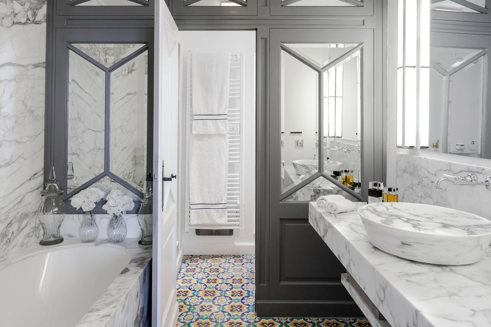 Inredning av ett klassiskt badrum, med öppna hyllor, ett hörnbadkar, vita väggar, mosaikgolv, ett fristående handfat och flerfärgat golv