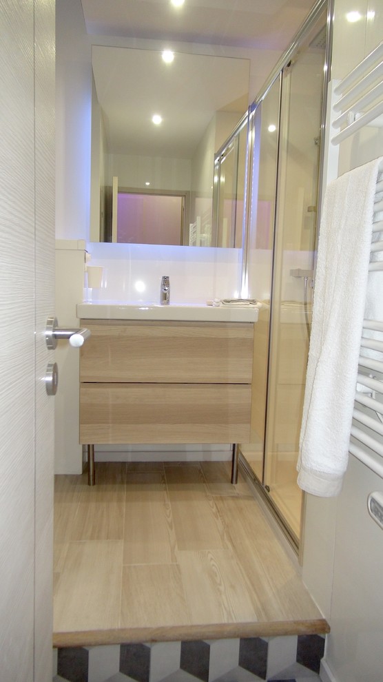 Walk-in shower - small contemporary 3/4 beige tile light wood floor walk-in shower idea in Nice with a trough sink, flat-panel cabinets, light wood cabinets, solid surface countertops, a wall-mount toilet and beige walls
