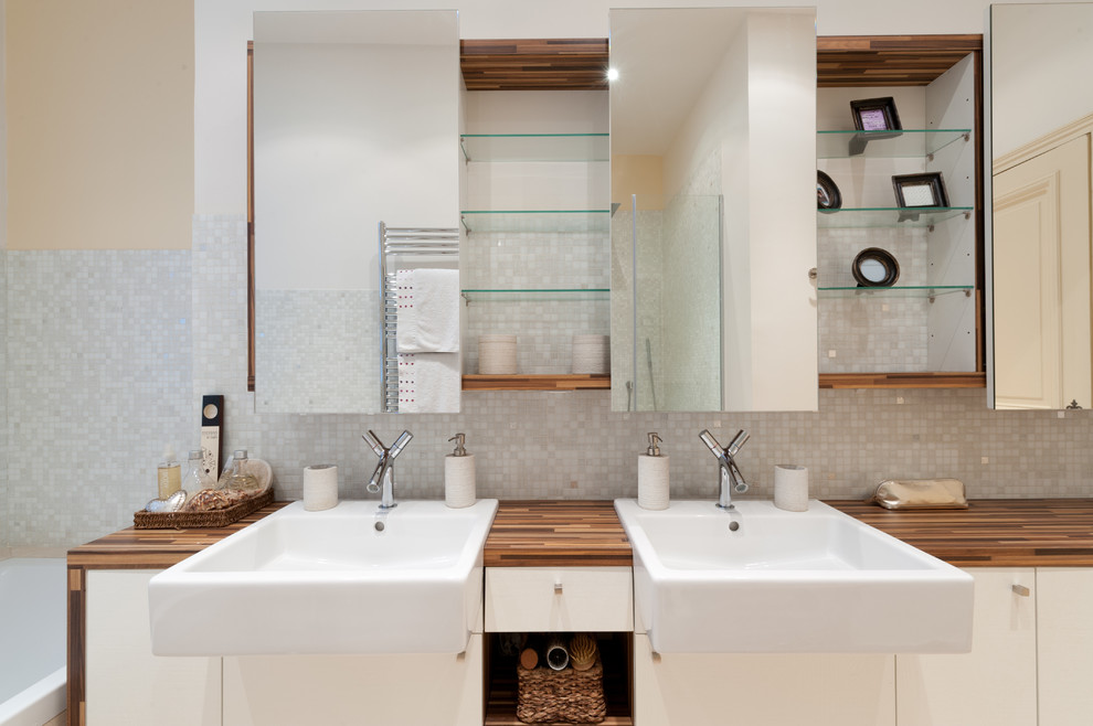 Modelo de cuarto de baño principal clásico renovado de tamaño medio con encimera de madera, paredes beige, bañera encastrada, baldosas y/o azulejos grises y lavabo bajoencimera