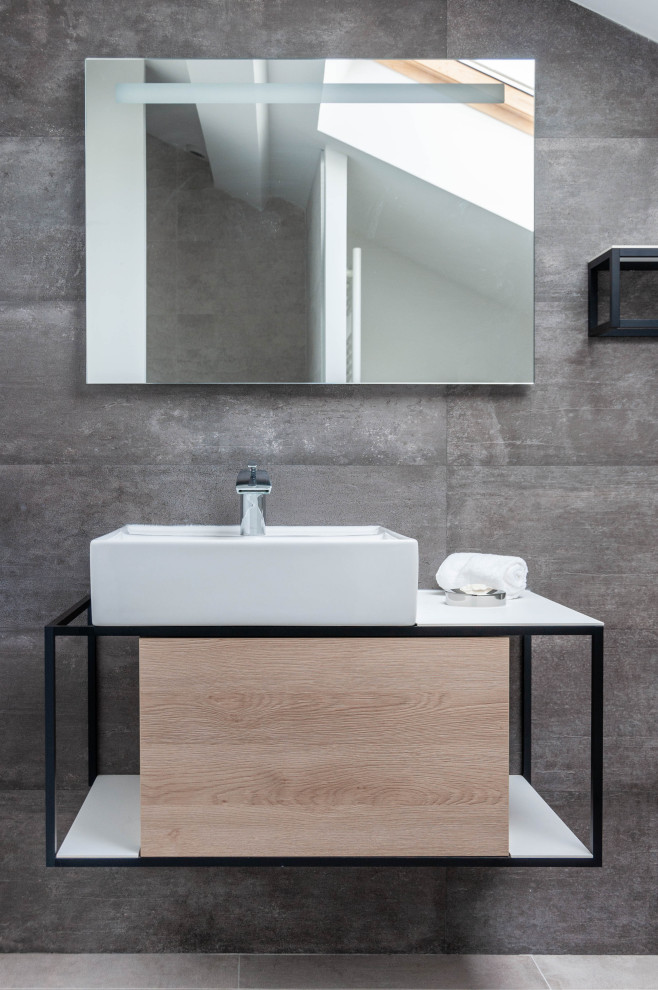 Inredning av ett industriellt mellanstort vit vitt en-suite badrum, med en kantlös dusch, en toalettstol med hel cisternkåpa, grå kakel, keramikplattor och ett nedsänkt handfat