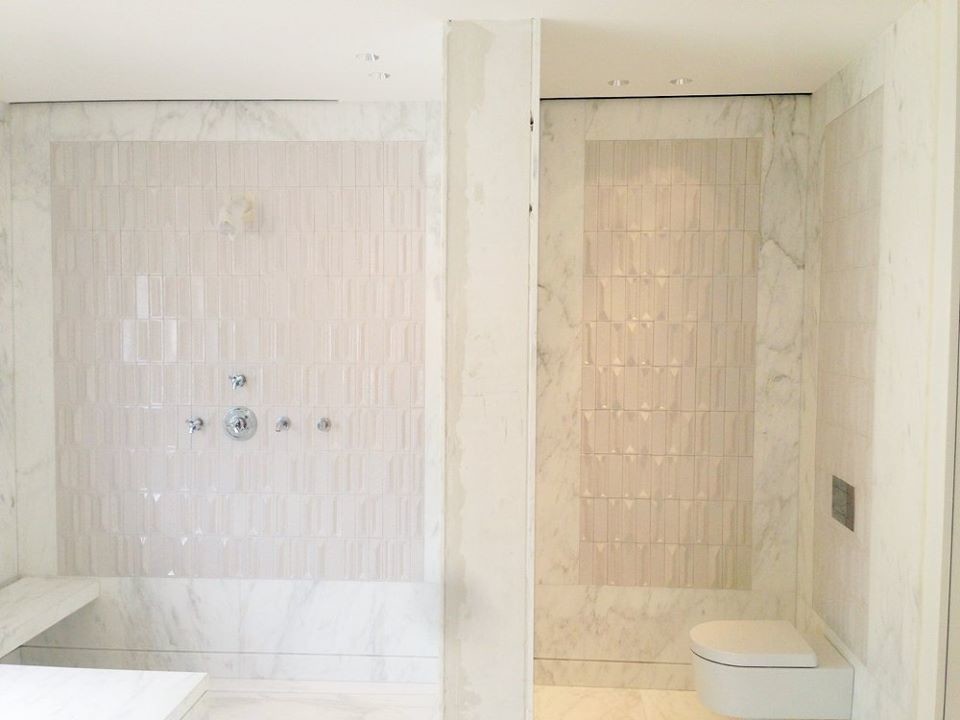 Cette image montre une grande salle d'eau traditionnelle avec une douche à l'italienne, WC suspendus, un mur blanc et un sol en marbre.