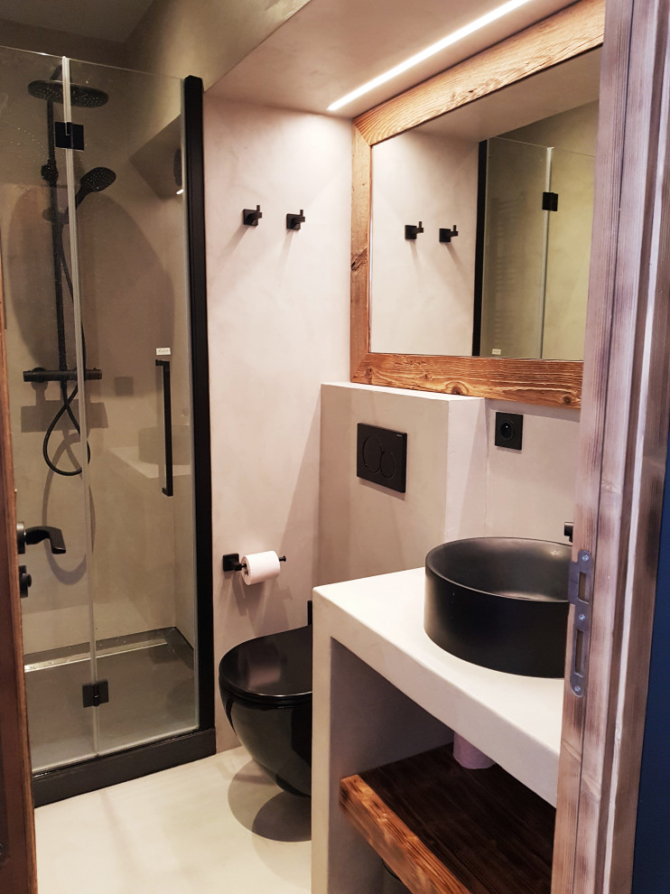 Modelo de cuarto de baño rural pequeño con ducha empotrada, sanitario de pared, paredes grises, suelo de cemento, lavabo encastrado, encimera de cemento, suelo gris, ducha con puerta con bisagras y encimeras grises