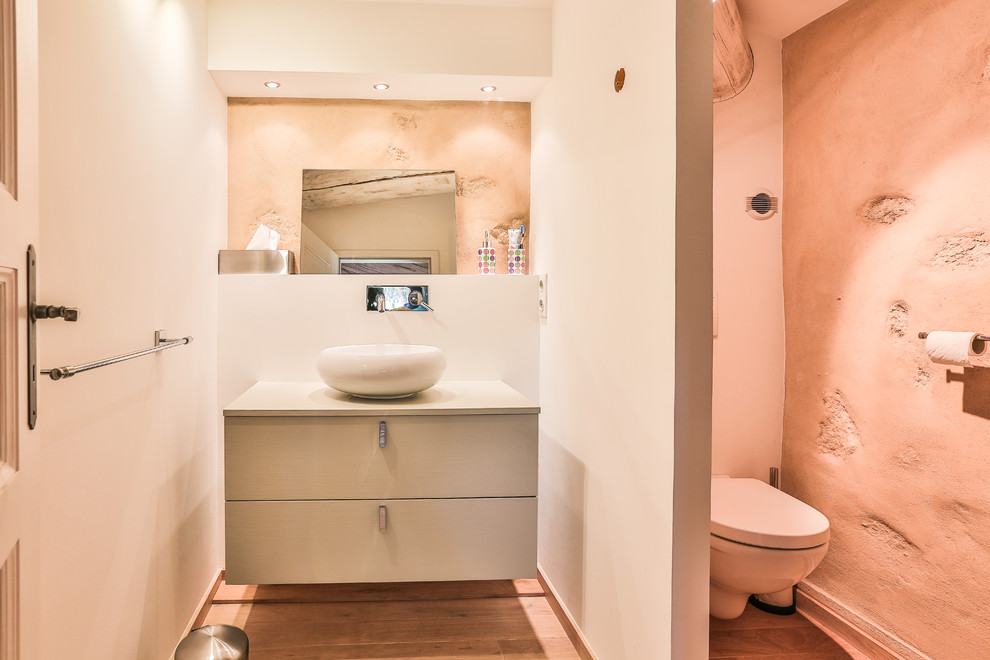 Inspiration for a small contemporary bathroom in Strasbourg with a vessel sink, flat-panel cabinets, light wood cabinets, a wall mounted toilet, dark hardwood flooring, beige walls and wooden worktops.