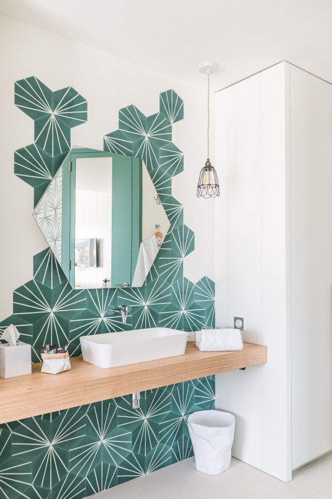 Mediterranes Badezimmer mit grünen Fliesen, weißer Wandfarbe, Aufsatzwaschbecken, Waschtisch aus Holz und grauem Boden in Sonstige