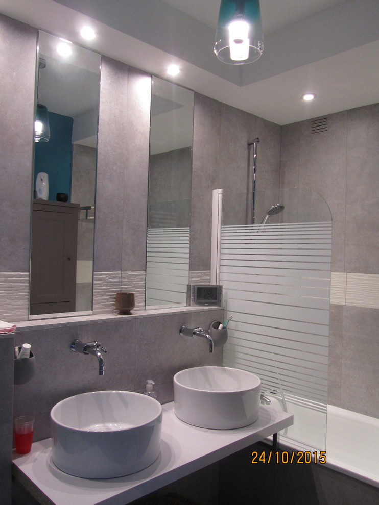 Bild på ett funkis badrum för barn, med ett väggmonterat handfat, laminatbänkskiva, ett platsbyggt badkar, en dusch/badkar-kombination, en vägghängd toalettstol, vit kakel, keramikplattor, grå väggar och klinkergolv i keramik