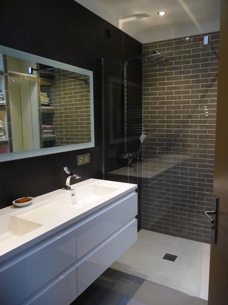 Large contemporary ensuite bathroom in Montpellier with a wall-mounted sink, glass-front cabinets, grey cabinets, a built-in shower, black tiles, stone tiles, grey walls and ceramic flooring.