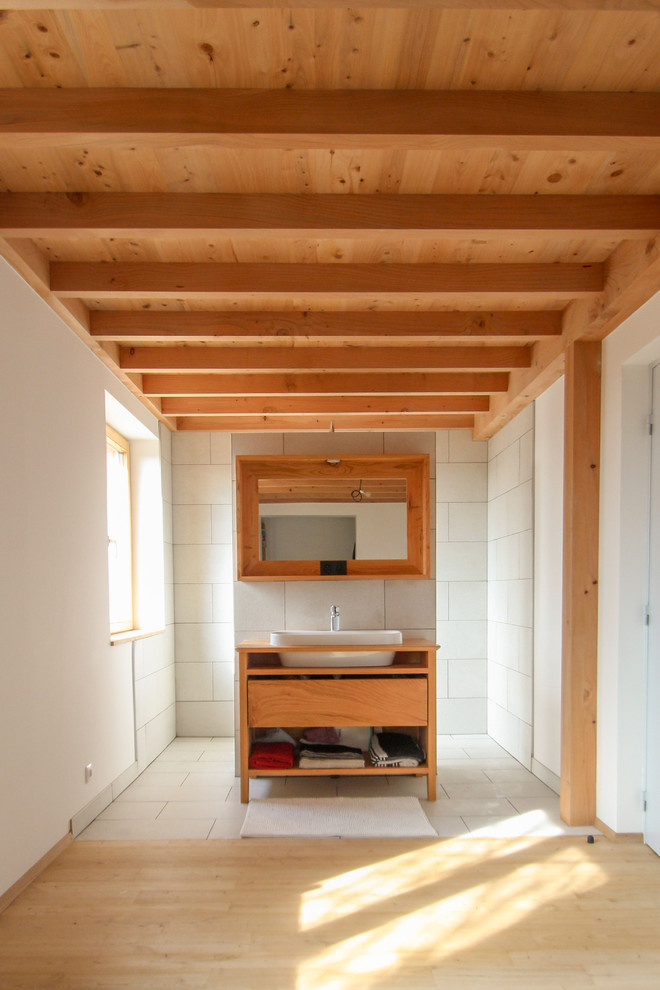Cette image montre une salle d'eau nordique avec un placard à porte plane, une douche à l'italienne, un lavabo posé et un plan de toilette en bois.