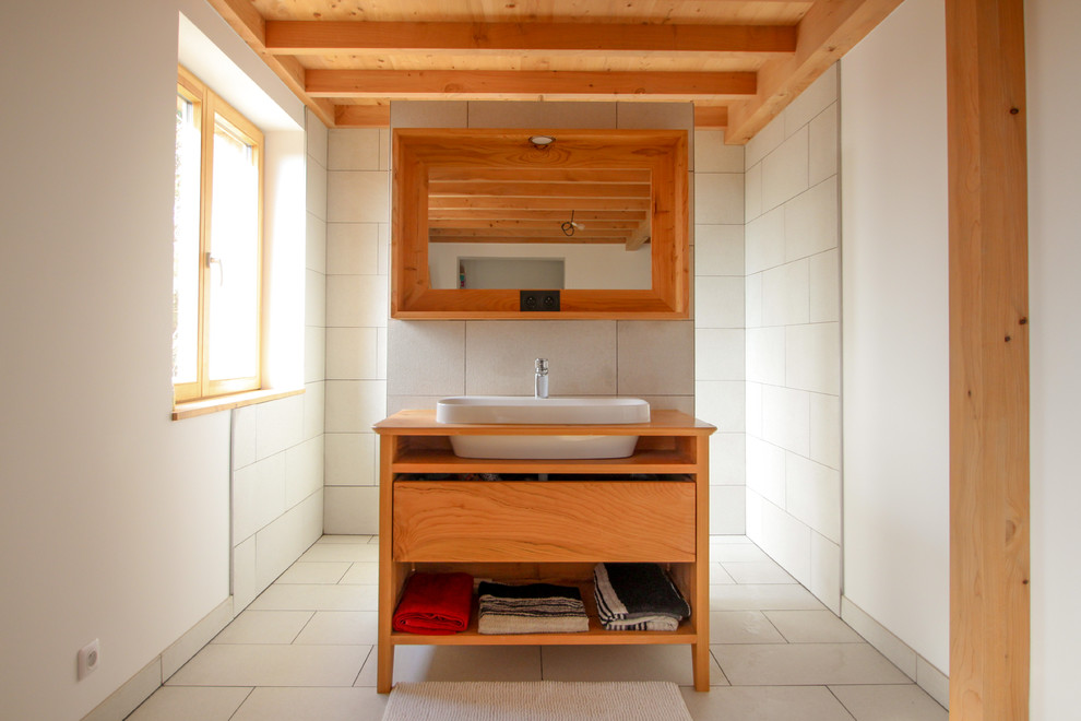 Inredning av ett modernt brun brunt badrum, med släta luckor, skåp i mellenmörkt trä, en kantlös dusch, vit kakel, vita väggar, ett nedsänkt handfat, träbänkskiva, vitt golv och med dusch som är öppen