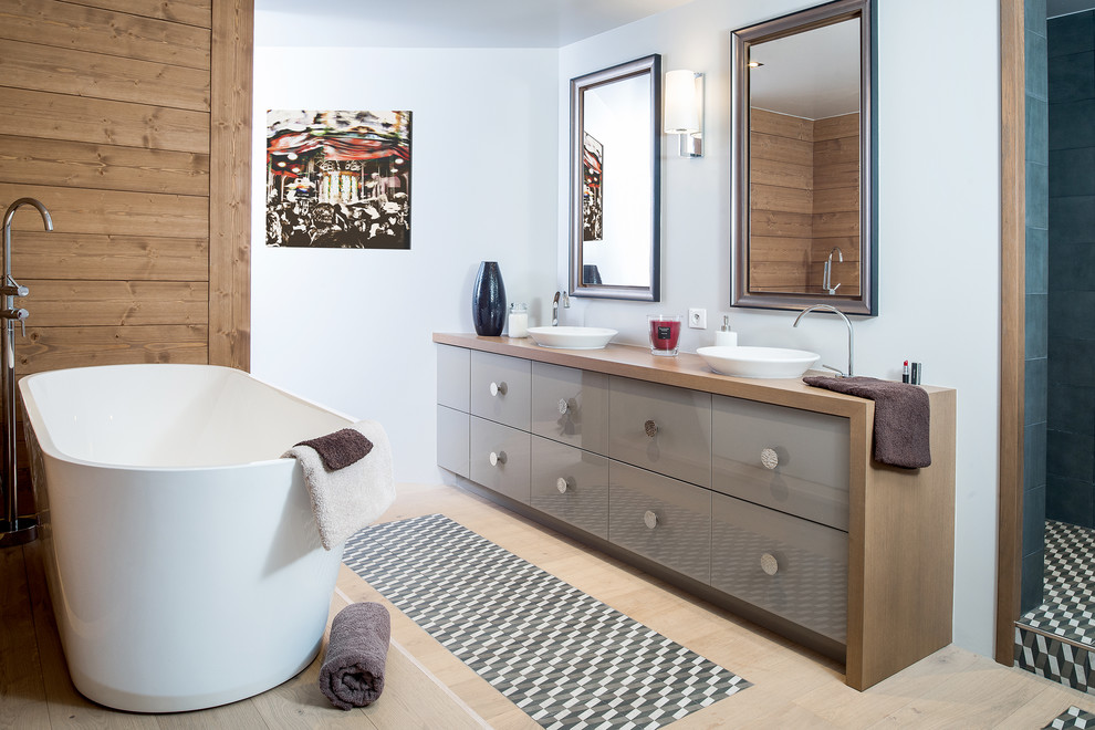 На фото: главная ванная комната среднего размера в современном стиле с отдельно стоящей ванной, белыми стенами, светлым паркетным полом, настольной раковиной, столешницей из дерева, коричневыми фасадами, душем в нише, коричневой столешницей и зеркалом с подсветкой с