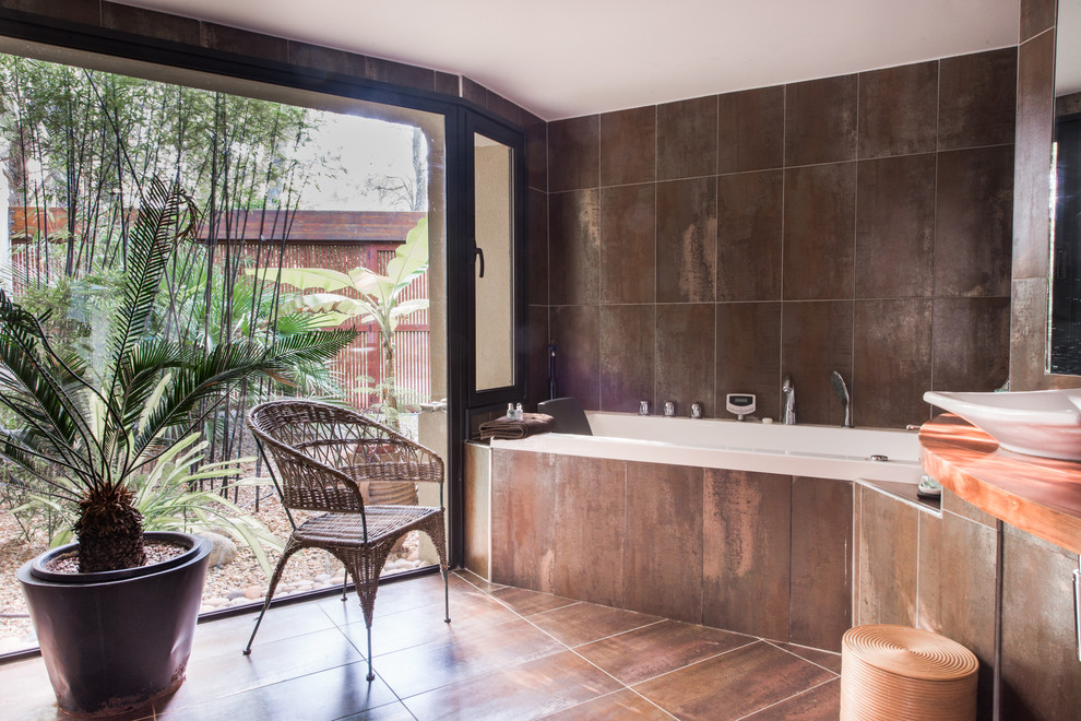 Imagen de cuarto de baño asiático con bañera encastrada, baldosas y/o azulejos marrones y lavabo sobreencimera