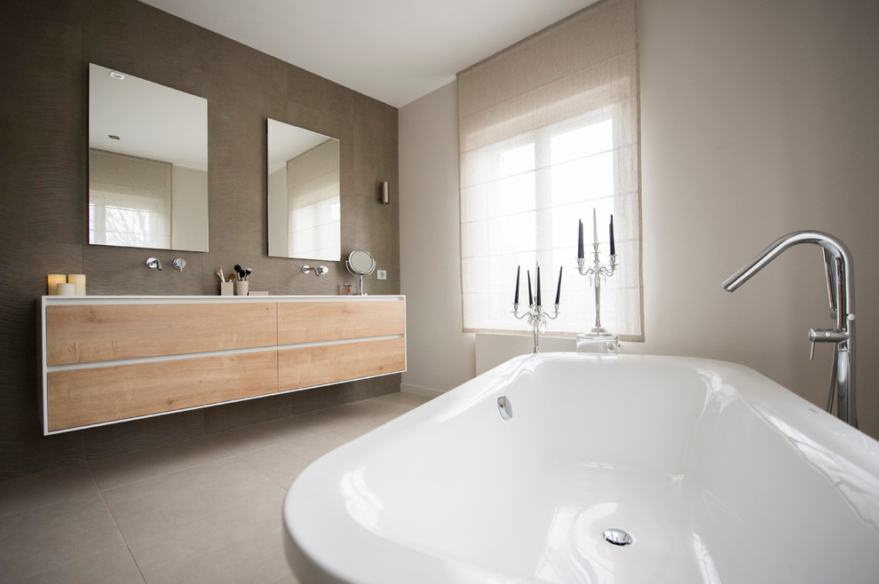 Large contemporary ensuite bathroom in Lyon with light wood cabinets, a freestanding bath, ceramic flooring, flat-panel cabinets and grey walls.
