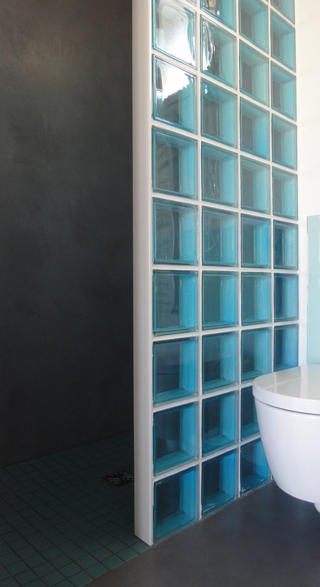 Diseño de cuarto de baño contemporáneo con ducha a ras de suelo, sanitario de pared, paredes blancas, suelo de cemento, lavabo encastrado y encimera de cemento