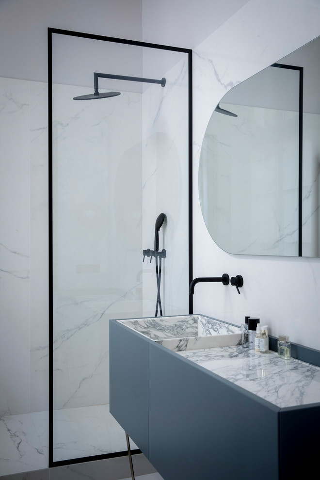 Стильный дизайн: ванная комната в современном стиле с плоскими фасадами, серыми фасадами, угловым душем, белой плиткой, белыми стенами, монолитной раковиной, белым полом, открытым душем и белой столешницей - последний тренд