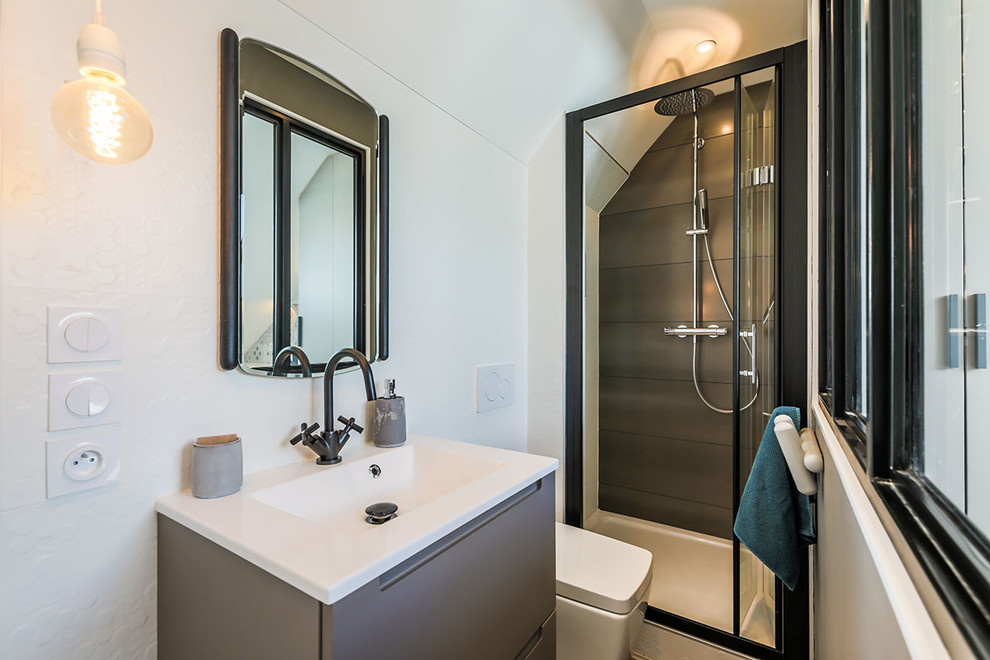 Aménagement d'une salle de bain contemporaine avec un placard à porte plane, des portes de placard grises, WC suspendus, un mur blanc, un plan vasque et une cabine de douche à porte battante.
