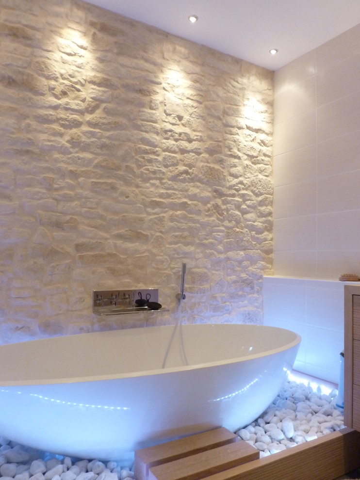 Photo of a medium sized contemporary bathroom in Grenoble with beaded cabinets, beige cabinets, a freestanding bath, beige tiles, limestone tiles, beige walls, wooden worktops and beige worktops.