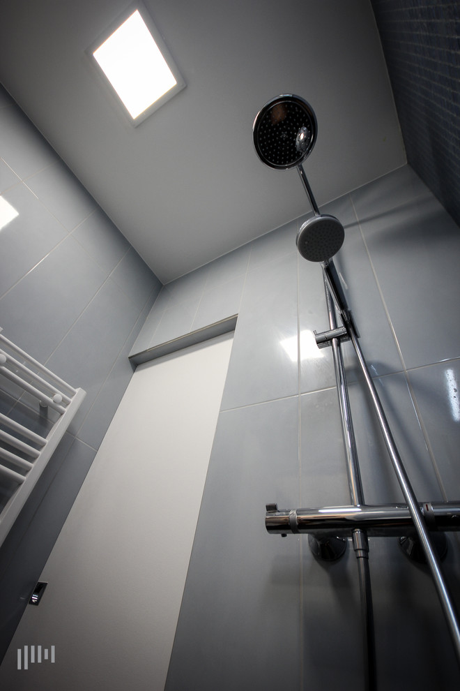 Ejemplo de cuarto de baño contemporáneo pequeño con ducha a ras de suelo, sanitario de pared, baldosas y/o azulejos grises, baldosas y/o azulejos en mosaico, paredes grises, suelo de pizarra, aseo y ducha, lavabo encastrado y encimera de vidrio