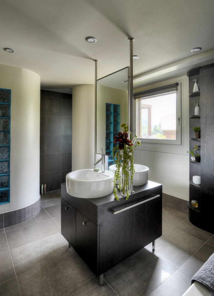 Exemple d'une salle de bain principale tendance en bois foncé de taille moyenne avec un placard à porte plane, un carrelage gris, un mur blanc et une vasque.