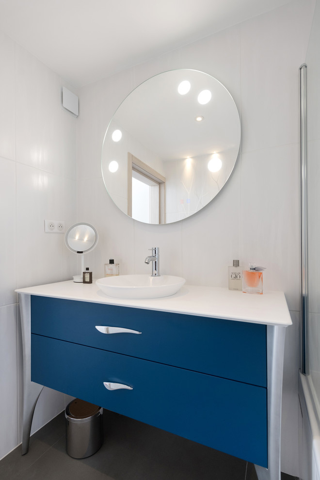 Exemple d'une salle de bain tendance de taille moyenne avec des portes de placard bleues, une baignoire encastrée, un combiné douche/baignoire, un carrelage blanc, des carreaux de céramique, un plan de toilette en bois et un plan de toilette blanc.