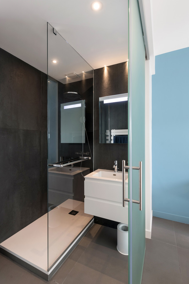 Idee per una stanza da bagno con doccia contemporanea di medie dimensioni con ante di vetro, ante bianche, doccia aperta, piastrelle nere, piastrelle in ceramica, pareti blu, pavimento in cemento, top in superficie solida, pavimento grigio e top bianco