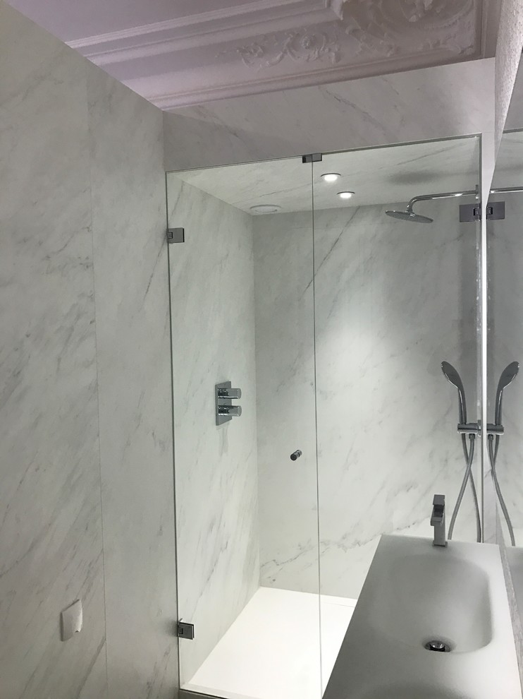Foto på ett mellanstort funkis badrum med dusch, med luckor med profilerade fronter, vita skåp, en kantlös dusch, vit kakel, keramikplattor, vita väggar, klinkergolv i keramik, ett konsol handfat, kaklad bänkskiva, vitt golv och dusch med gångjärnsdörr