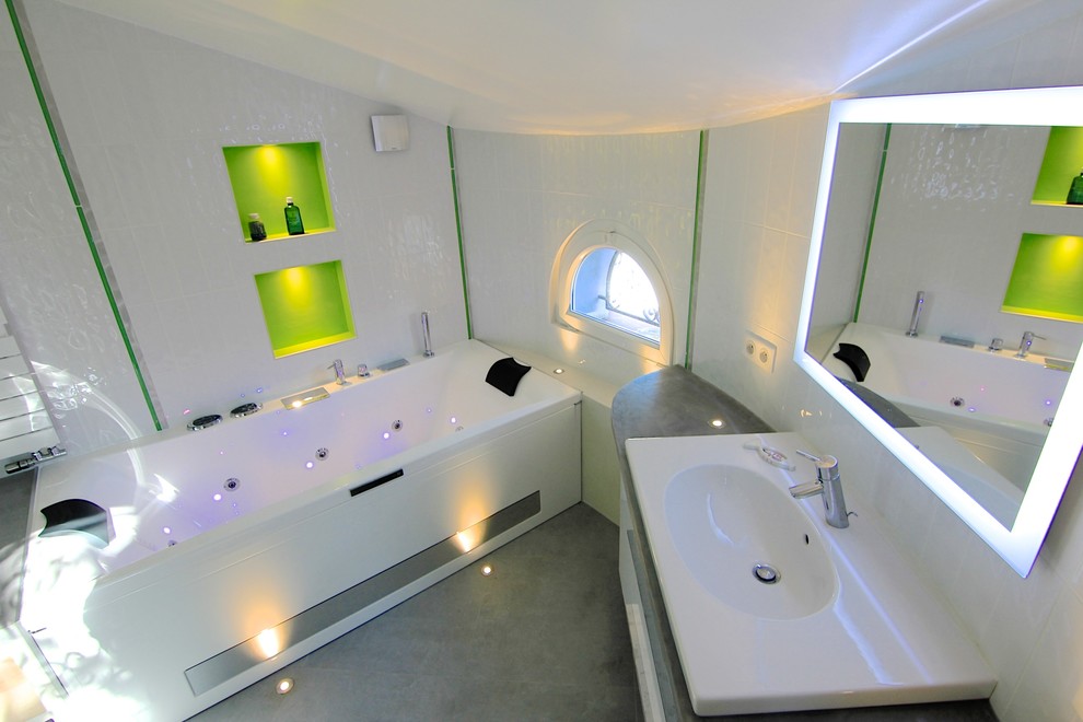 Idéer för att renovera ett stort funkis en-suite badrum, med öppna hyllor, gröna skåp, en jacuzzi, en kantlös dusch, en toalettstol med separat cisternkåpa, vit kakel, porslinskakel, vita väggar, klinkergolv i keramik, ett avlångt handfat och bänkskiva i betong