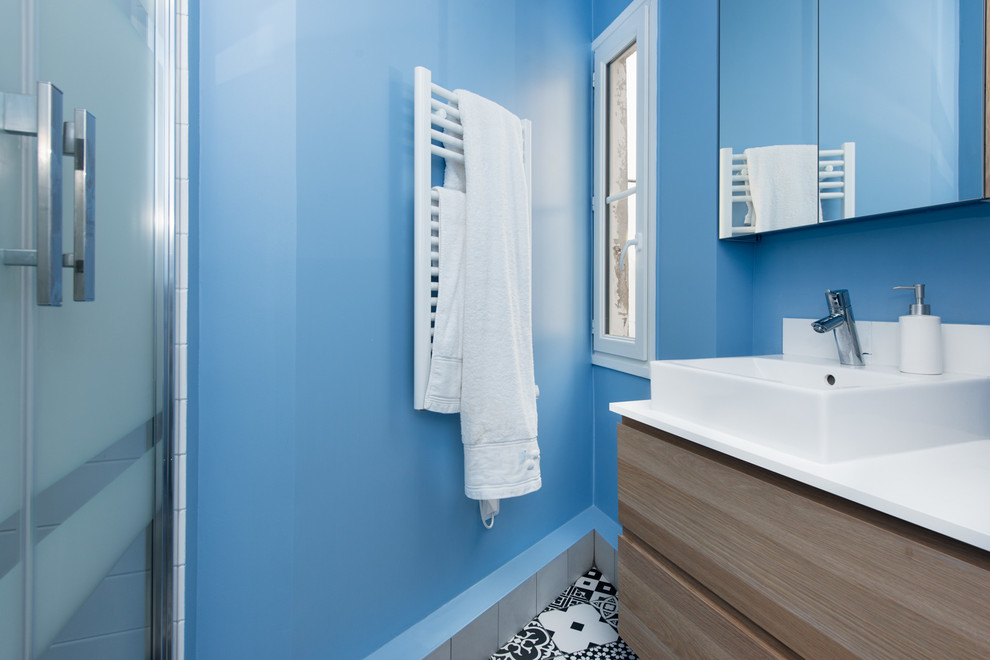 Idéer för mellanstora funkis en-suite badrum, med luckor med profilerade fronter, en kantlös dusch, en toalettstol med separat cisternkåpa, svart och vit kakel, cementkakel, blå väggar, klinkergolv i keramik, ett avlångt handfat och bänkskiva i akrylsten