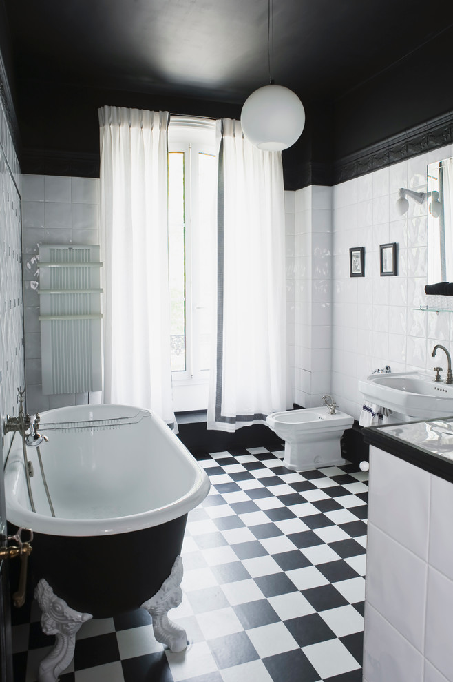Cette image montre une salle de bain principale traditionnelle de taille moyenne avec un lavabo de ferme, une baignoire sur pieds, un bidet, un carrelage blanc, un carrelage noir et blanc et un mur blanc.