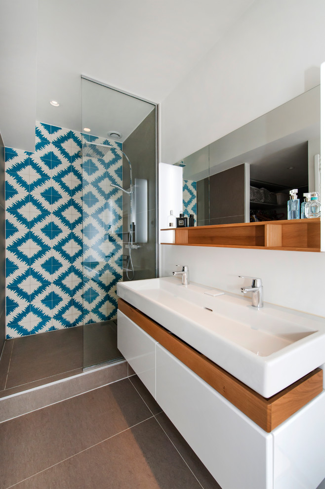 На фото: ванная комната в скандинавском стиле с плоскими фасадами, белыми фасадами, душем в нише, синей плиткой, разноцветной плиткой, белой плиткой, белыми стенами, душевой кабиной, раковиной с несколькими смесителями и серым полом с