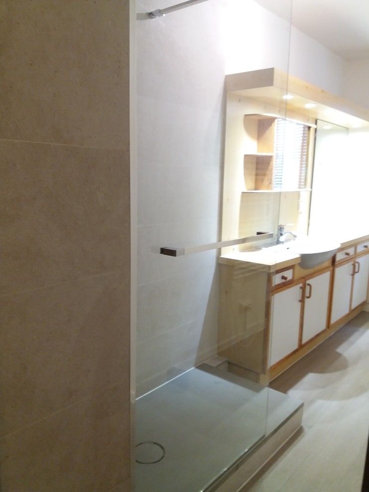 Foto de cuarto de baño actual con ducha a ras de suelo, baldosas y/o azulejos de piedra, paredes beige, suelo vinílico, aseo y ducha y suelo beige