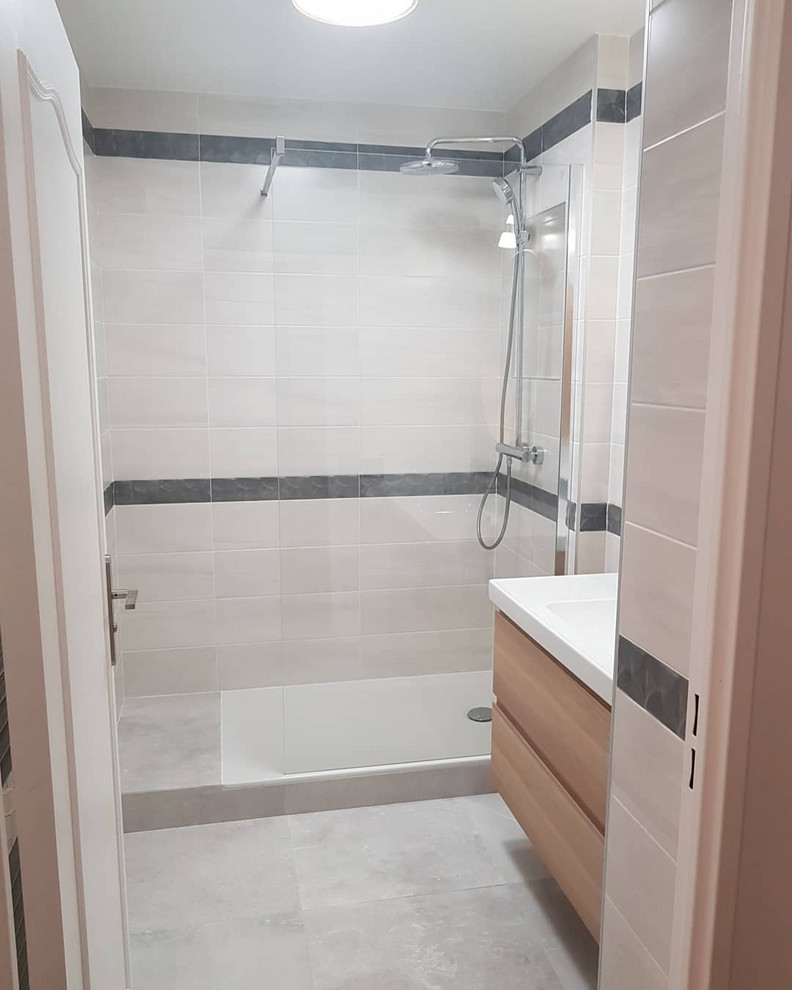 Inredning av ett modernt mellanstort vit vitt badrum med dusch, med luckor med profilerade fronter, skåp i ljust trä, en kantlös dusch, grå kakel, keramikplattor, grå väggar, klinkergolv i keramik, ett konsol handfat och grått golv