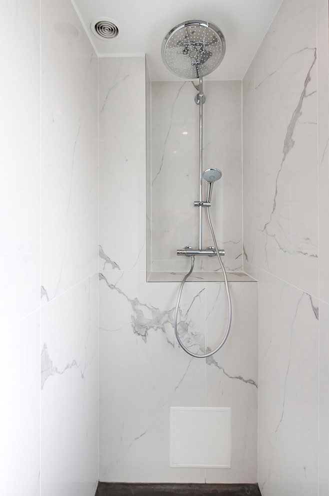 Inredning av ett modernt mellanstort vit vitt badrum med dusch, med släta luckor, vita skåp, en kantlös dusch, en toalettstol med separat cisternkåpa, vit kakel, grå kakel, marmorkakel, blå väggar, marmorgolv, ett avlångt handfat, vitt golv och med dusch som är öppen