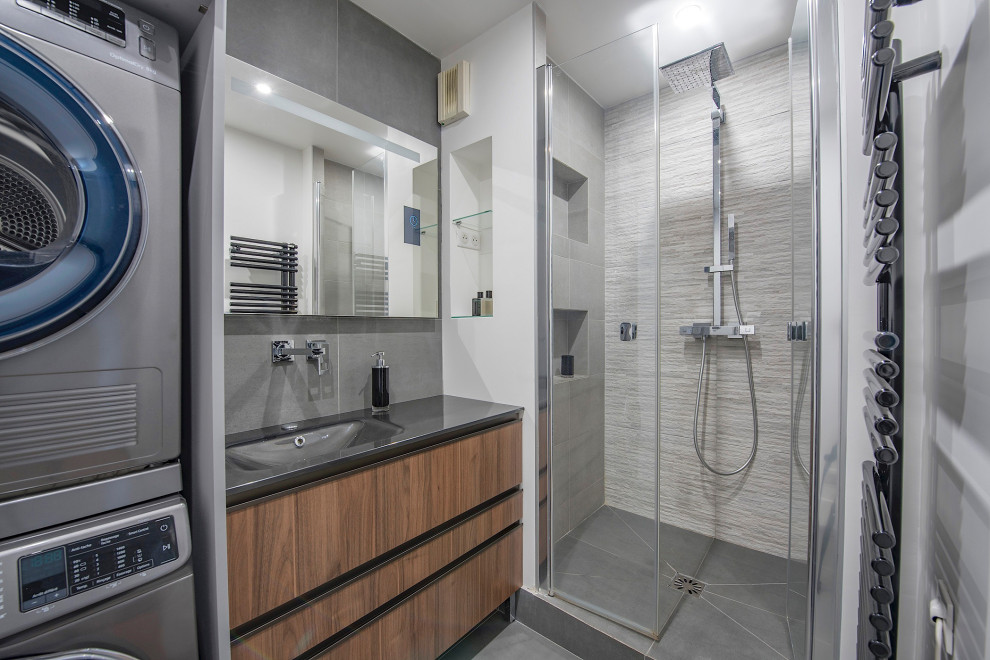Inspiration för mellanstora moderna grått badrum med dusch, med skåp i mellenmörkt trä, grå kakel, klinkergolv i keramik, bänkskiva i glas, släta luckor, en dusch i en alkov, vita väggar, ett undermonterad handfat, grått golv och dusch med gångjärnsdörr