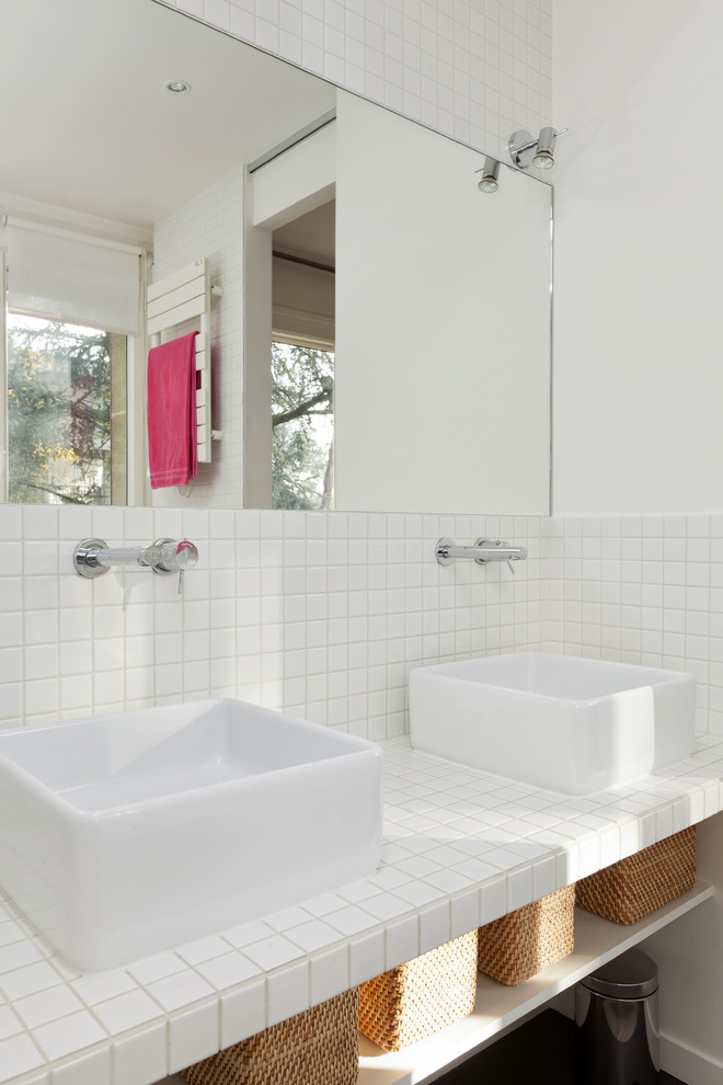 Cette photo montre une salle de bain tendance de taille moyenne avec un mur blanc, parquet foncé, une vasque, un plan de toilette en carrelage, un carrelage blanc, un placard sans porte et des portes de placard blanches.