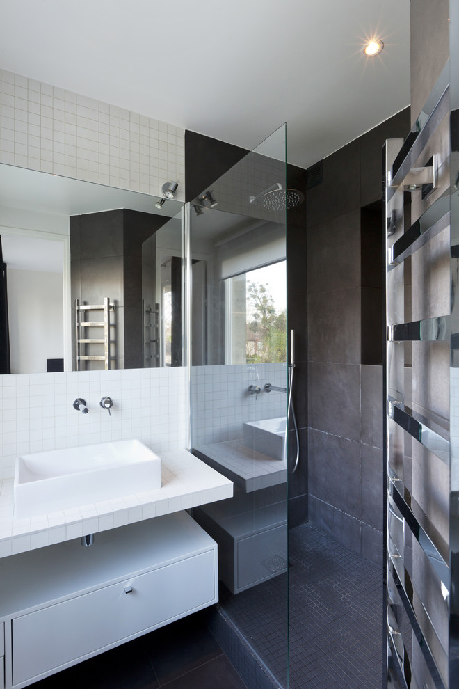 Cette photo montre une salle de bain tendance avec un placard à porte plane, un carrelage gris, un carrelage blanc, des carreaux de céramique, un sol en carrelage de céramique, une vasque, des portes de placard blanches et un mur blanc.