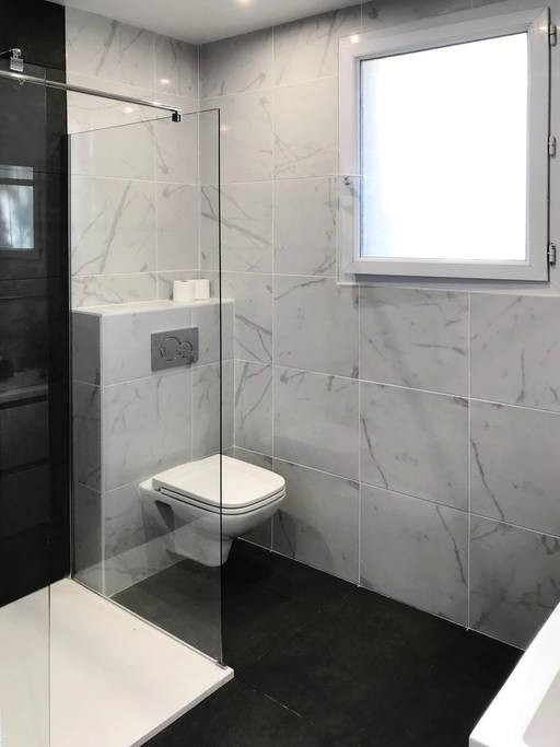 Idées déco pour une salle de bain principale contemporaine de taille moyenne avec WC suspendus, des carreaux de béton, un mur blanc, un sol noir et aucune cabine.
