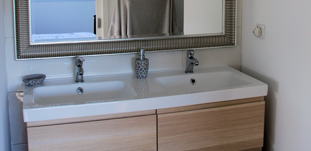 Réalisation d'une salle de bain design en bois clair avec un placard à porte affleurante, un mur blanc et un lavabo encastré.