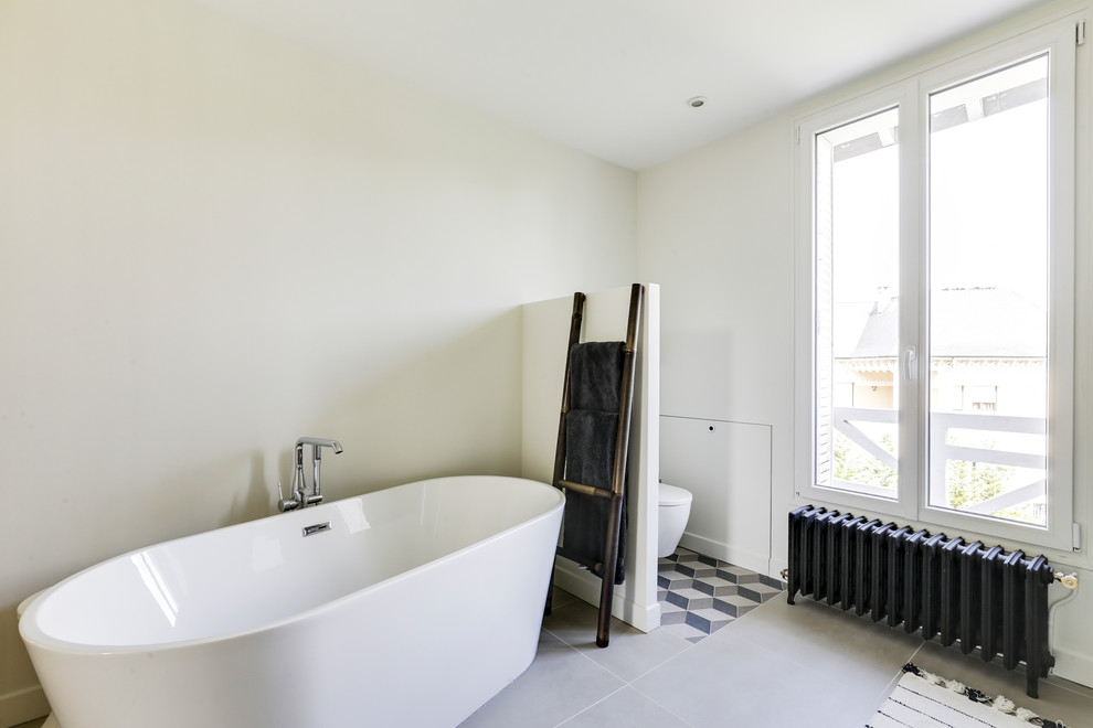 This is an example of a medium sized contemporary ensuite bathroom in Paris with beaded cabinets, light wood cabinets, a freestanding bath, a built-in shower, white walls, a built-in sink, grey floors, an open shower and white worktops.
