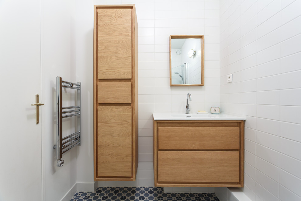 Design ideas for a small scandinavian ensuite bathroom in Paris with flat-panel cabinets, light wood cabinets, an alcove shower, a wall mounted toilet, white tiles, porcelain tiles, white walls, cement flooring, a console sink, solid surface worktops, blue floors, a hinged door, white worktops, a single sink and a floating vanity unit.