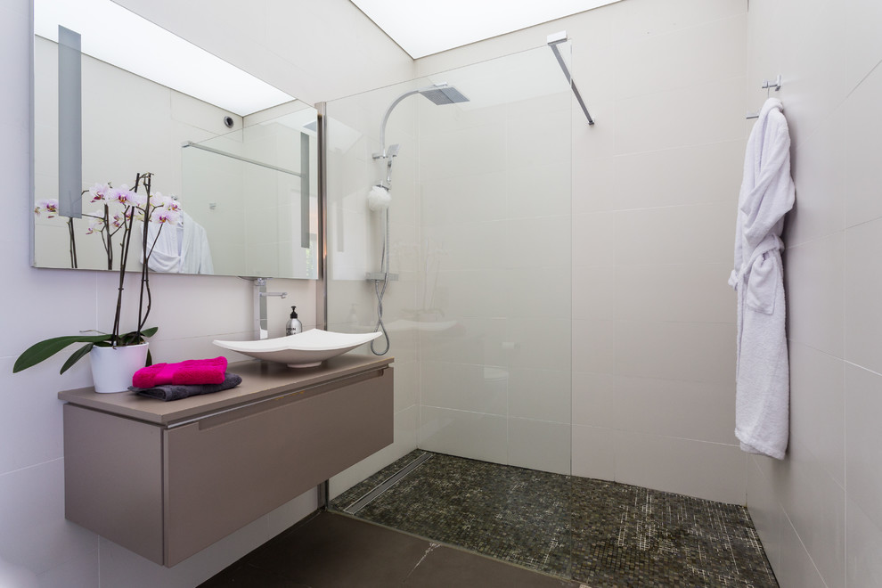 Foto de cuarto de baño actual de tamaño medio con aseo y ducha, ducha a ras de suelo, paredes beige, lavabo sobreencimera y baldosas y/o azulejos blancos