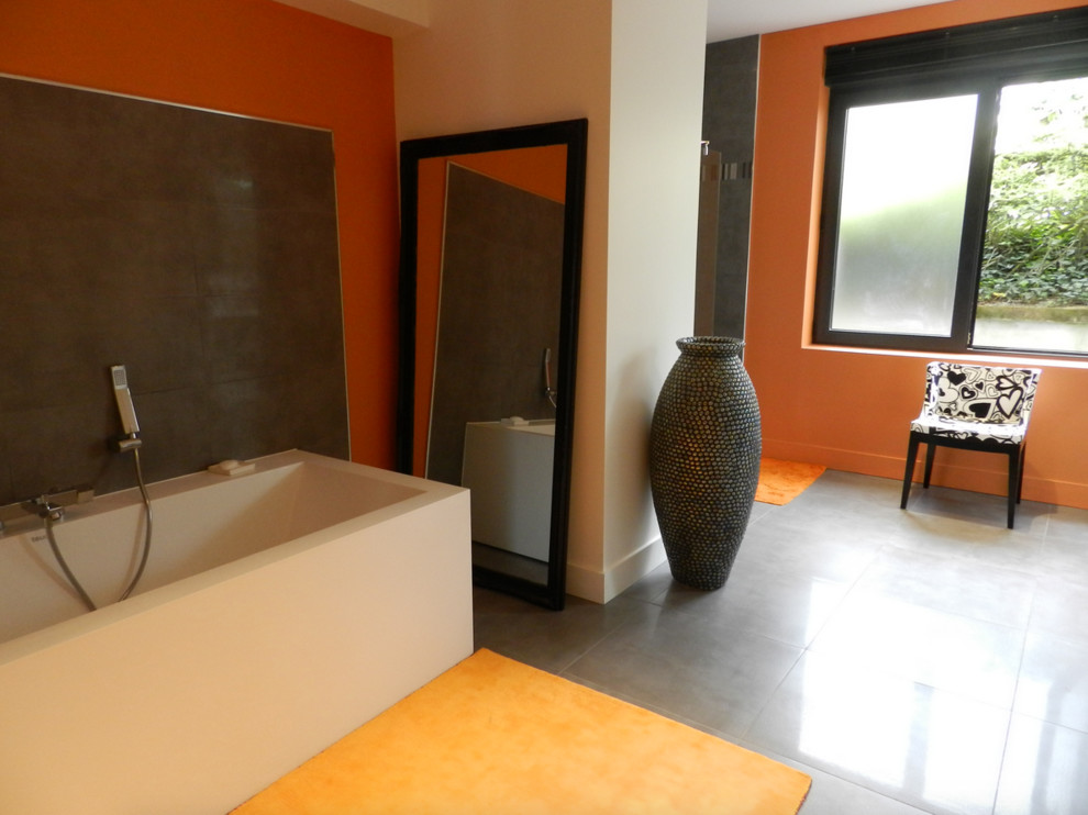 Cette photo montre une grande salle de bain tendance avec des portes de placard blanches, une baignoire posée, une douche à l'italienne, un carrelage gris, des carreaux de céramique, un mur orange, un sol en carrelage de céramique, une grande vasque, un plan de toilette en surface solide et un sol gris.