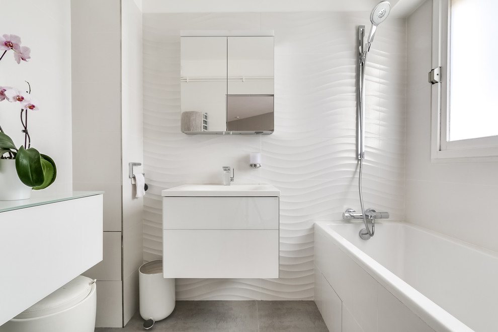 Пример оригинального дизайна: маленькая главная ванная комната в современном стиле с плоскими фасадами, белыми фасадами, ванной в нише, душем над ванной, белыми стенами, подвесной раковиной и открытым душем для на участке и в саду