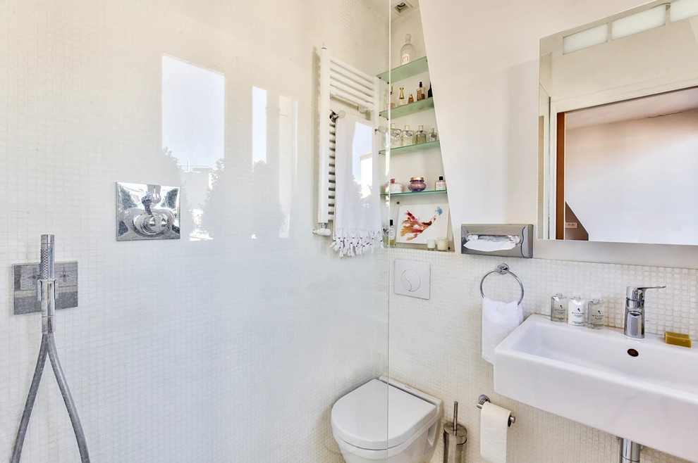 Modern inredning av ett litet vit vitt badrum med dusch, med vita skåp, en kantlös dusch, en vägghängd toalettstol, vit kakel, mosaik, vita väggar, mosaikgolv, ett fristående handfat, kaklad bänkskiva, vitt golv och med dusch som är öppen