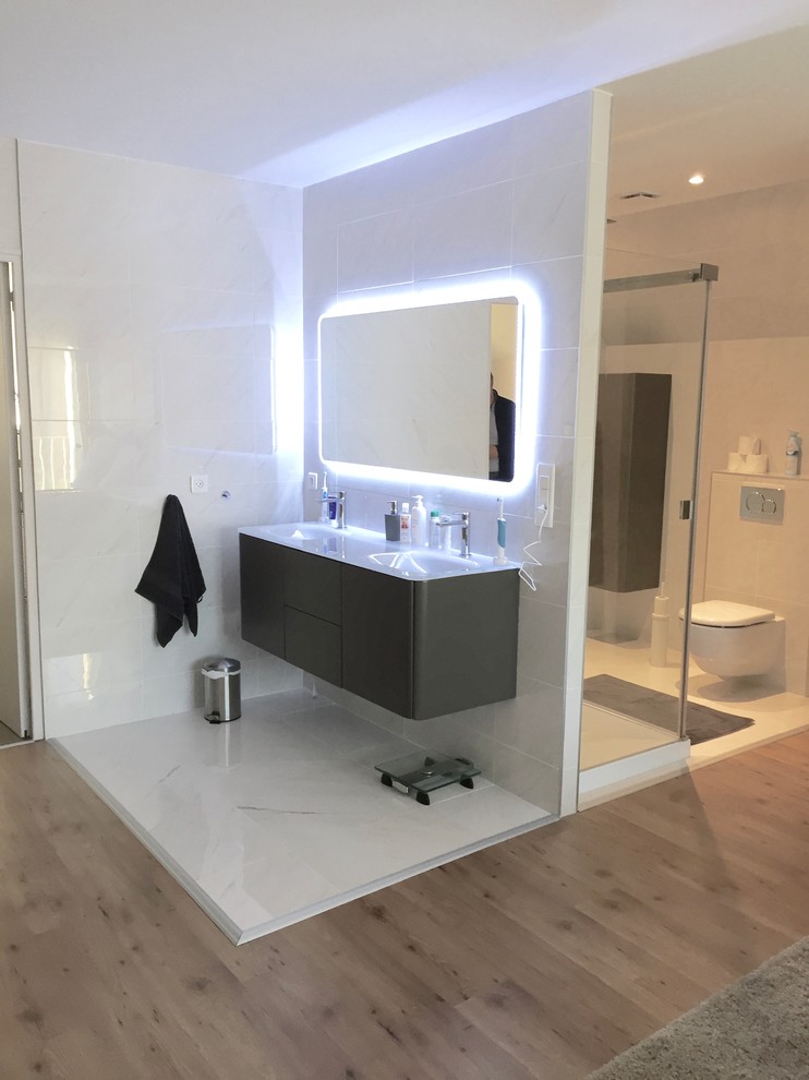 Inspiration pour une salle d'eau design de taille moyenne avec une douche double, WC suspendus, un carrelage blanc, un mur blanc, un sol en marbre, un lavabo encastré et un plan de toilette en verre.